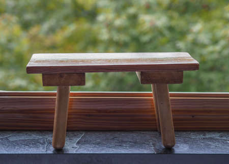 wooden bench on marble floor over blurred greenery background