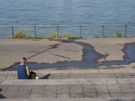 unrecognisable woman looking at river Rhine in Duesseldorf, Germany
