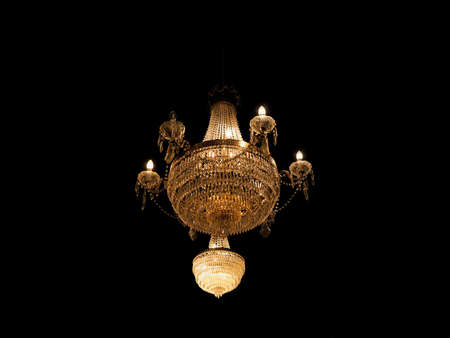 vintage chandelier, warm yellow light over black backgroundの写真素材