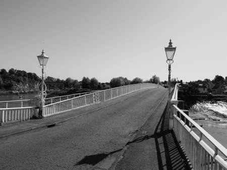 Old Wye Bridge crossing the river between Monmouthshire in Wales and Gloucestershire in England in Chepstow, UK in black and whiteの写真素材