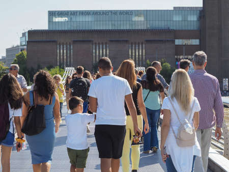 LONDON, UK - CIRCA SEPTEMBER 2019: People crossing Millennium Bridge over River Thames linking the...