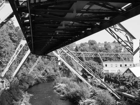 WUPPERTAL, GERMANY - CIRCA AUGUST 2019: Wuppertaler Schwebebahn (meaning Wuppertal Suspension Railway) above River Wupper is the oldest electric elevated railway with hanging cars in the world in black and whiteのeditorial素材