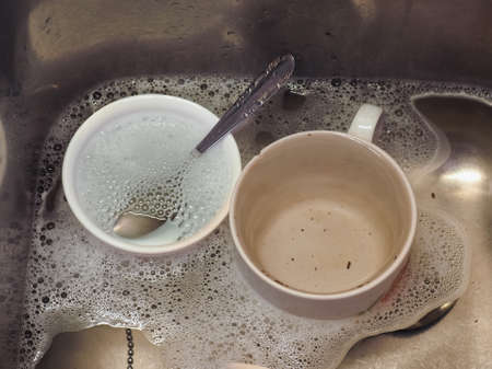 dish washing with tea cups in water with dishwashing liquitの写真素材
