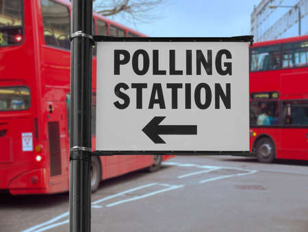 Polling station sign over double decker buses blurred backgroundの写真素材