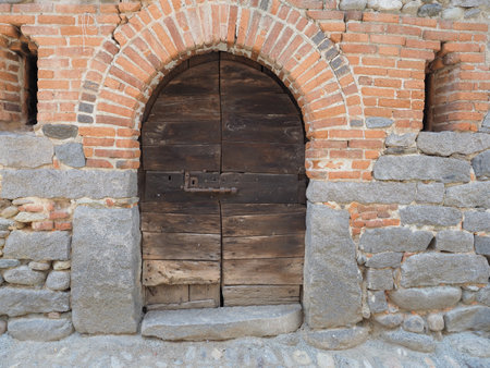 ancient medieval wooden door gate in stone and brick wallの写真素材