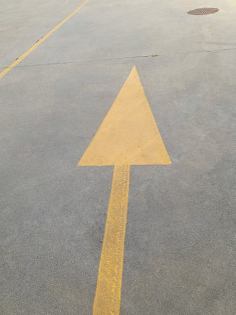 yellow arrow sign painted on concrete floorの写真素材
