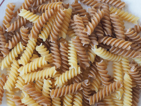 mixed regular and whole wheat fusilli pasta useful as a backgroundの写真素材