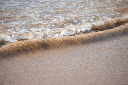 A ripple seen from above on the edge of the beach forming a pattern of parallel lines that cross the imageの写真素材