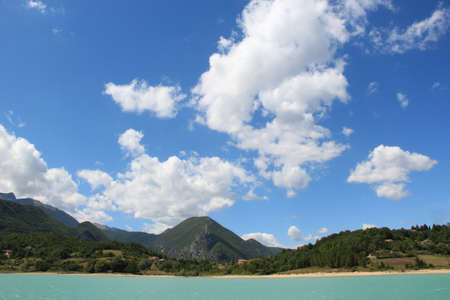 Panorama of a summer day, emerald lake and deep blue sky with clouds の写真素材