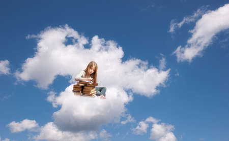Little girl sitting on a cloud who writesの写真素材