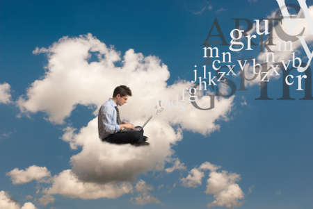 young man with laptop sitting on the cloudsの写真素材