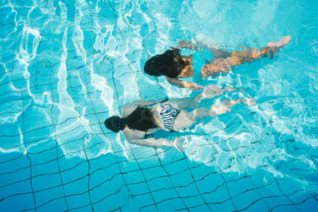 Girls swimming underwater in pool