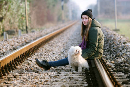 Teen girl with her dog on the railsの写真素材