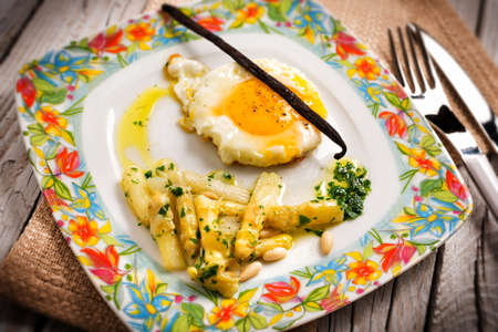 Fried egg with white asparagus and pine nutsの写真素材