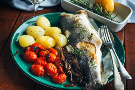 Sea bass baked with potatoes and tomatoes