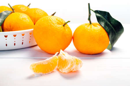 Pile of mandarins in white bowl on white wooden backgroundの写真素材