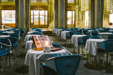 Venice, Italy, 23 December 2019 - outdoor bar tables in San Marco square in the evening. On the table in the foreground a burning candleのeditorial素材