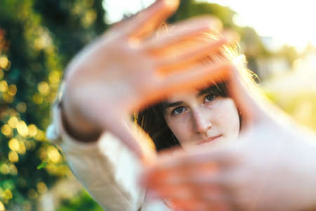 Portrait of cute girl outdoors with frame hands in front of faceの写真素材