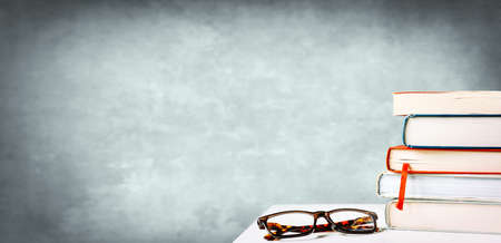 Stack of books on the table and a pair of reading glassesの写真素材