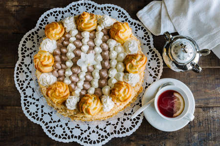 Cream cake decorated with cream puffs filled with cream and chocolate. St. HonorÃ© cake