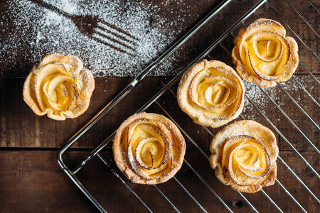 Pastries with custard decorated with apple slices in the shape of a rose on wooden boardsの写真素材