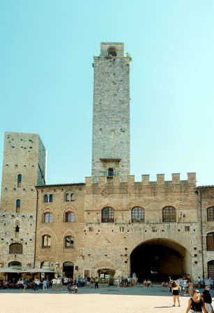 San Gimignano, Italy - August 23, 2020: tourists in the Duomo square, in the background some of the famous medieval towers. Some tourists wear coronavirus (COVID-19) masksのeditorial素材
