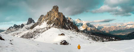 Man with yellow vest admiring the panorama of the snowy mountains. Ampezzo Dolomites.の写真素材