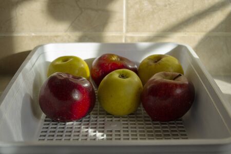 red and yellow apples in white basketの写真素材