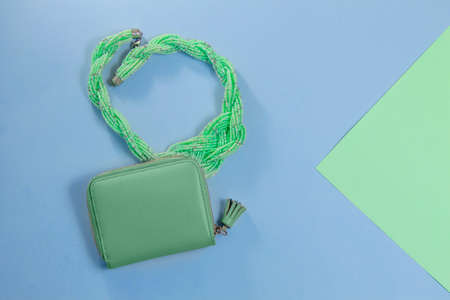 women's green necklace and wallet on blue and green backgroundの写真素材