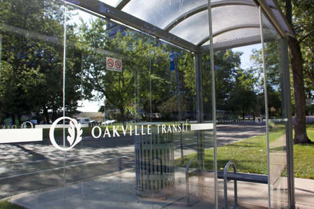 Oakville, Ontario / Canada - September 11, 2020: Oakville transit logo on the transparent glass of a shelter at the bus stop in a green residential neighbourhood.のeditorial素材