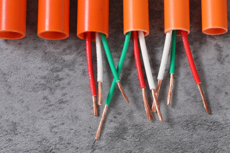 Electrical wires in orange and green color on gray background, close upの写真素材