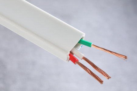 Electrical cable with copper and green wires on a gray background.の写真素材