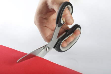 Scissors cut red paper on a white background, close-upの写真素材
