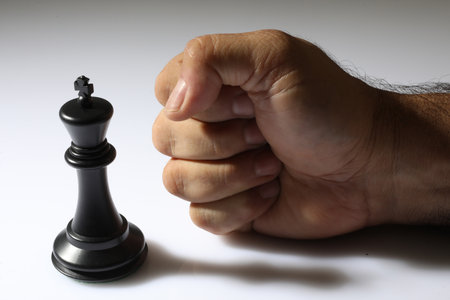 Close up of black chess king in hand isolated on white background.