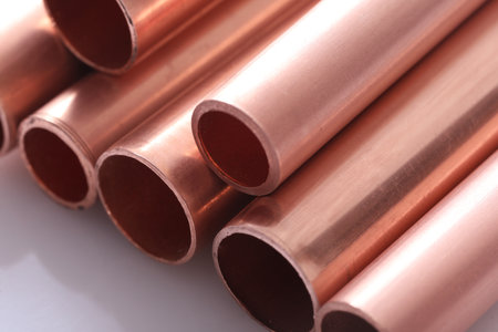 Copper pipes of different diameters lie on a white background.