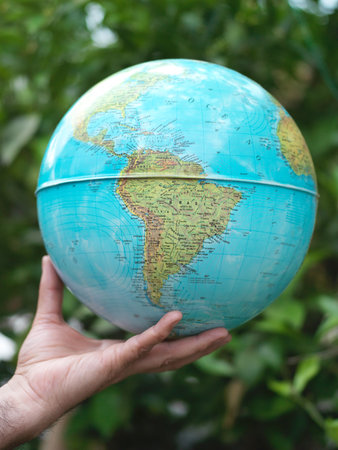 Hand holding a globe on a blurred background of nature. Close-upの写真素材