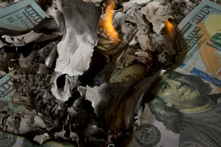 Burning dollar banknotes on a dark background close up