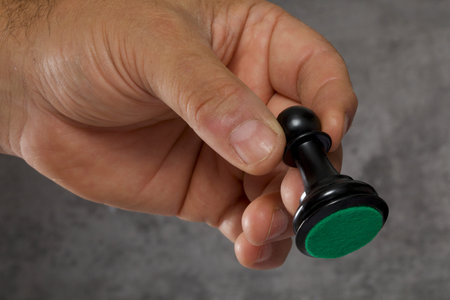 Close-up of a man's hand holding a black chess pieceの写真素材