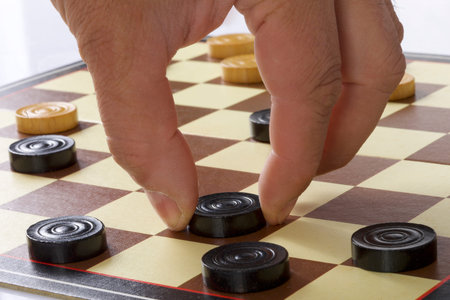 Close up of a checkerboard game with chess pieces and hand