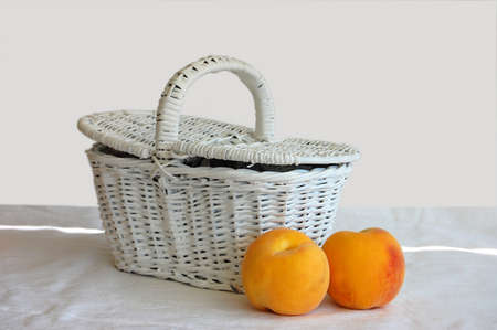 basket with two peaches on white backgroundの写真素材