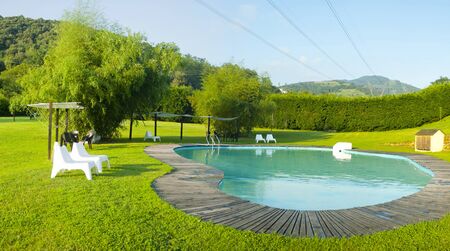 Camijanes, Spain, July, 9, 2018. Panorama of a swimming pool surrounded by greenery in a relaxing and sunny setting at sunset.のeditorial素材