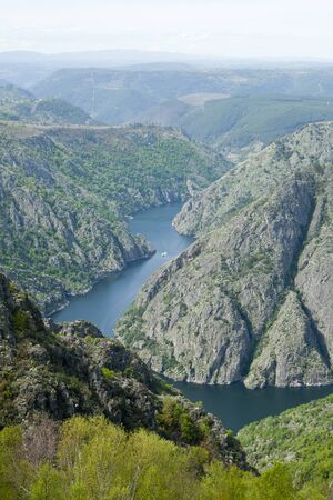 River at the bottom of a canyon with a boat sailing its waters. Sil river between Lugo and Orense provinces in Galicia region, Spain.のeditorial素材