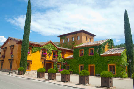 TORREMOCHA, SPAIN / MAY 29, 2022 typical Castilian building with orange facade, with ivy and purple...