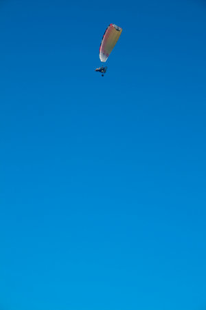 Paraglider with motor over the zenith of the observer and with blue sky in the background, The technical definition is: ultralight flexible gliderの写真素材