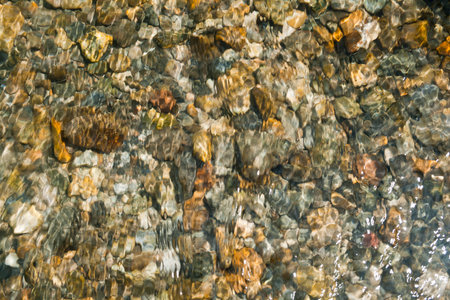 Texture of peebles covered in a layer of clear flowing water, Cinca river in Pineta valley, Huesca...