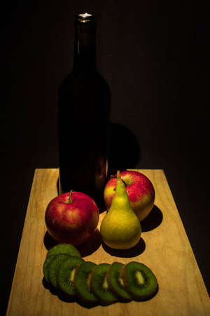 Bottle of wine with apples and pears on a wooden boardの写真素材