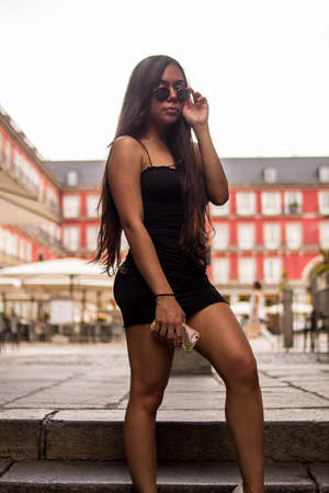 Selective focus of young hispanic woman posing on a summer day while strolling through a square in the cityの写真素材