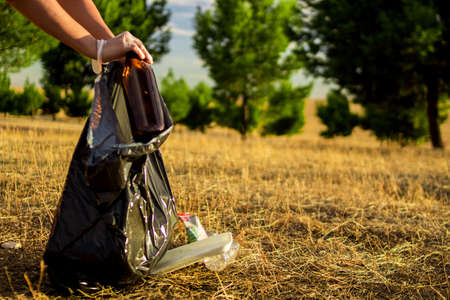 Image of the hands of a Caucasian woman collecting plastic garbage in a meadowの写真素材