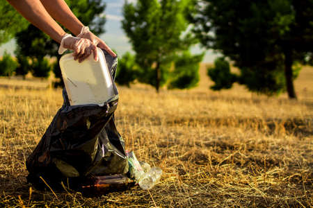 Image of the hands of a Caucasian woman collecting plastic garbage in a meadowの写真素材