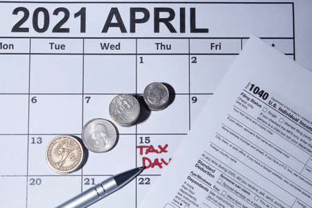 Tax day image with an april calendar a pen a calculator i coins for tax time